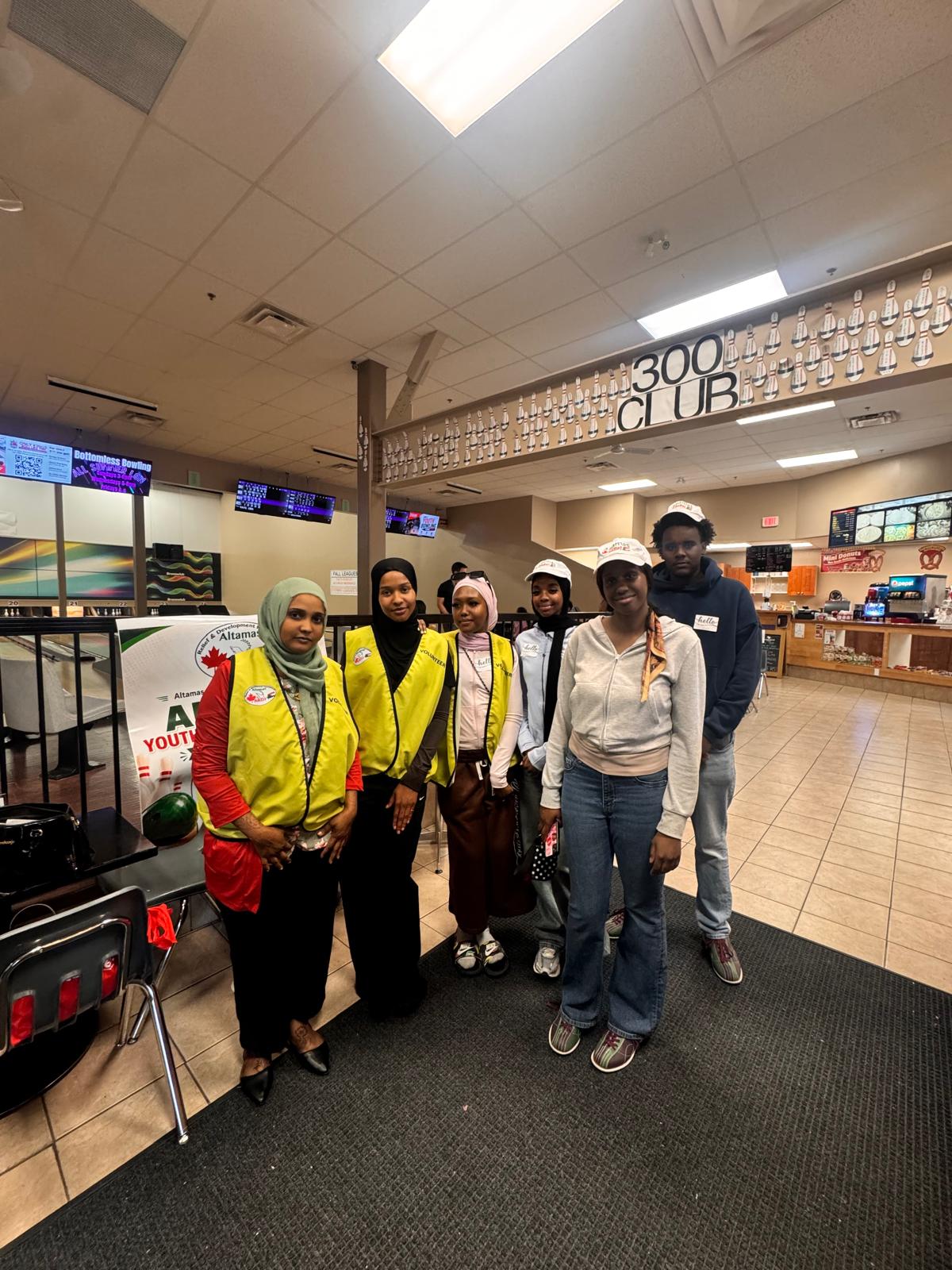 Altamas youth volunteers in high-visibility vests gathered together at a community bowling event